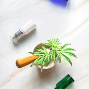 Cosmetic products on a marble table with a young sprout of hemp. Hemp products for body and face